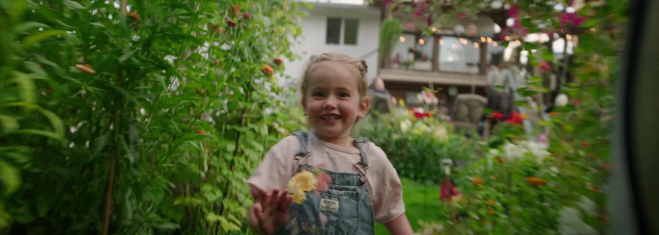 Smiling child running with open arms in a garden