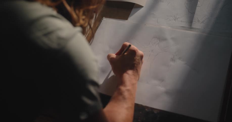 The man is sketching on the paper