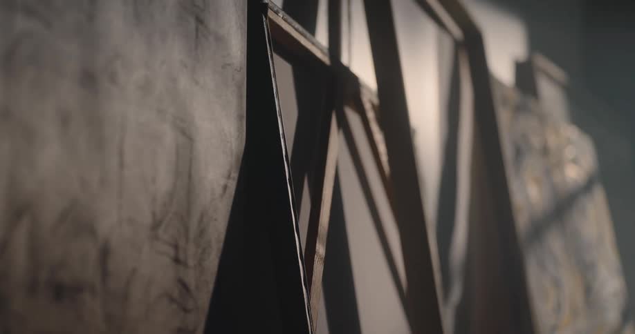 Large canvases leaning against the wall are softly lit in an art studio