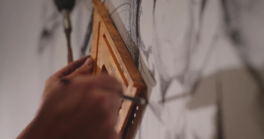 Closeup of hands drawing on a wall using a ruler