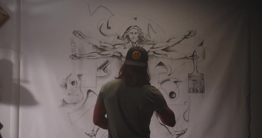 The man points and examines the drawing on the mural