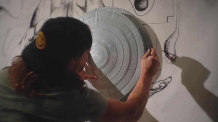 The artist is drawing on a large canvas