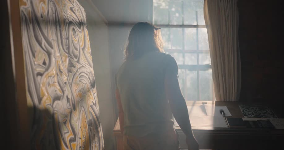Person standing in front of a desk illuminated by sunlight streaming through the window