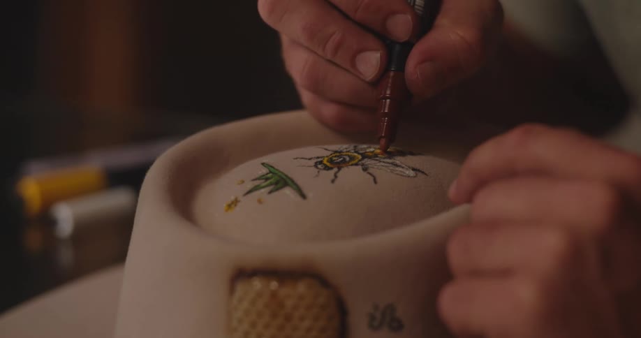 The man sketches a drawing on the hat