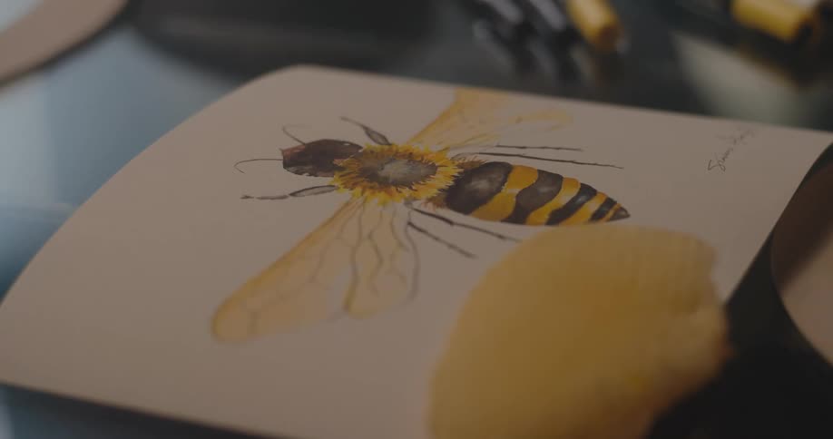Closeup of a watercolor painting of a bee placed on a table