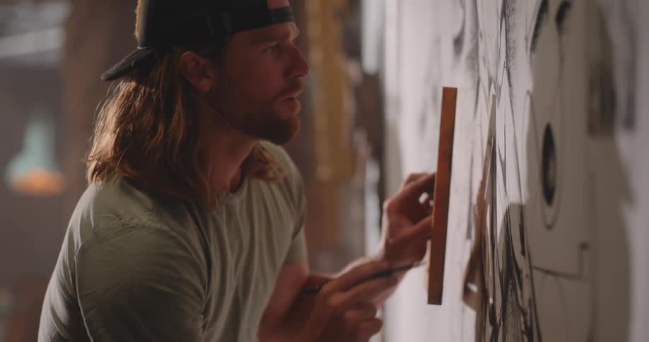 Man drawing on a large panel using a pencil and ruler