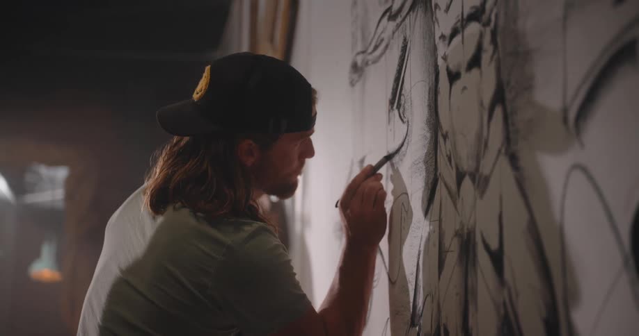Artist draws detailed lines on a large black and white mural
