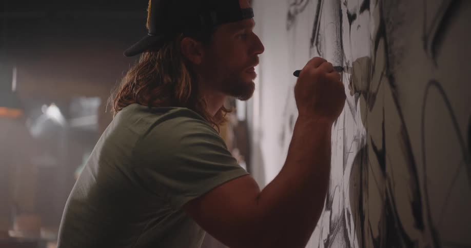 Artist drawing on a large mural with focus