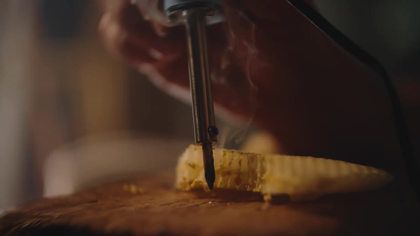 A person uses a soldering iron to melt a piece of plastic indoors