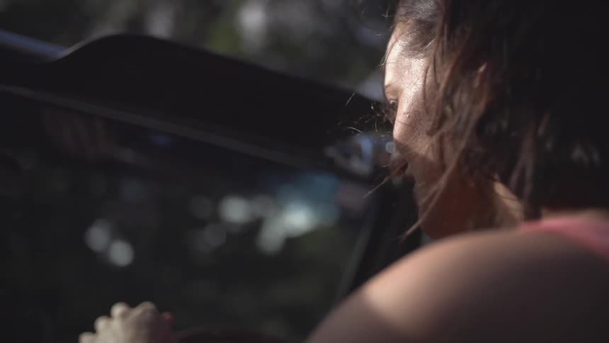 A young, dark-haired woman driving a jeep with its top removed