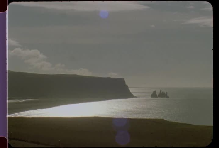 A video of the ocean with a large land mass or boulder sticking out