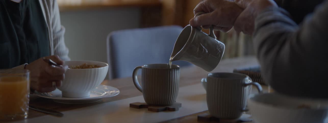 Pouring creamer into coffee in a green mug