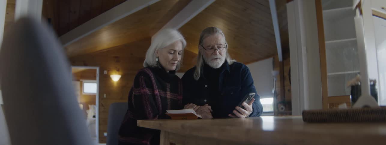 While looking at a cell phone a man and woman hold hands