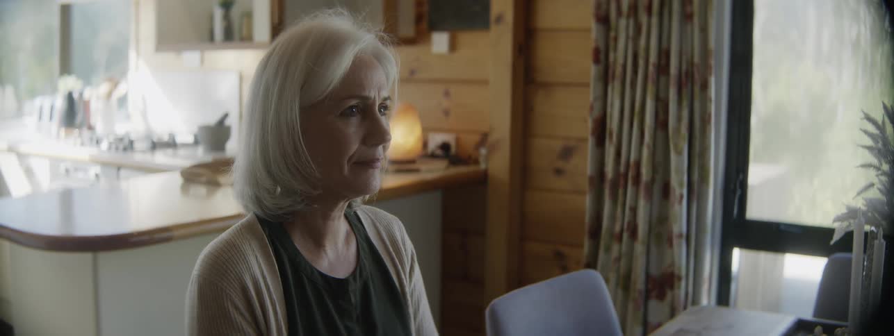 Close up portrait of a middle aged woman sitting at a dining table for a meal during daytime