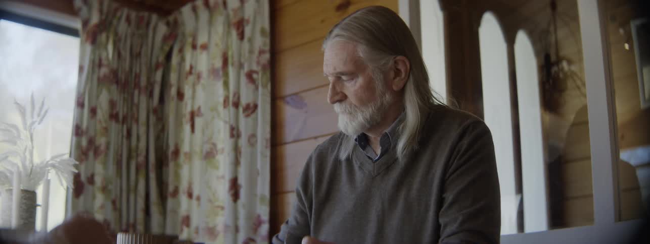 Man hands a mug to another person during a quiet moment at the table