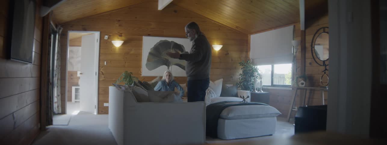 The man and woman search through the cushions on the couch