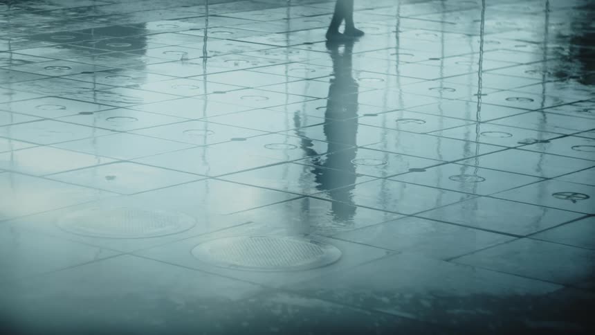 Reflection of a person running on a wet floor as water splashes around