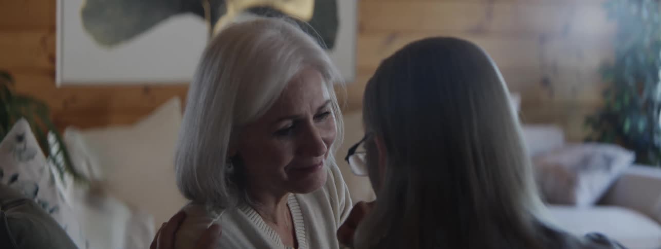 Close up of a middle aged man and woman conversing and consoling each other while sitting in a living room during daytime