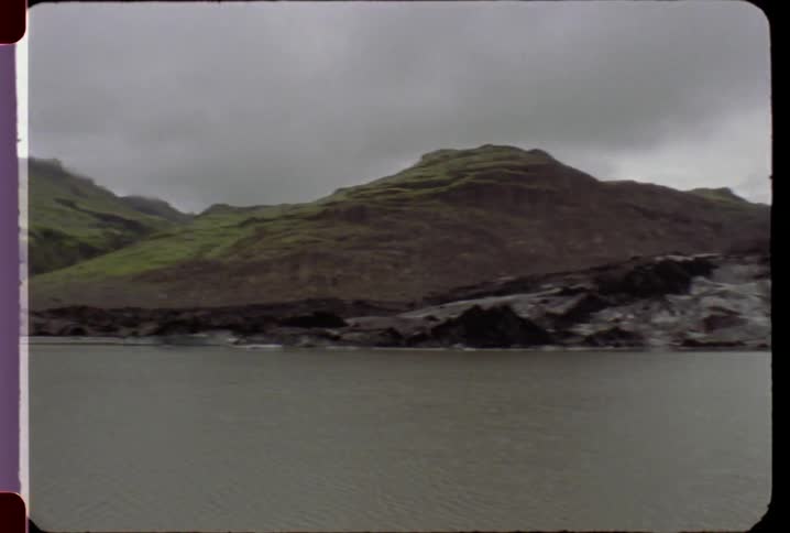 A lake in front of a hilly rocky landscape