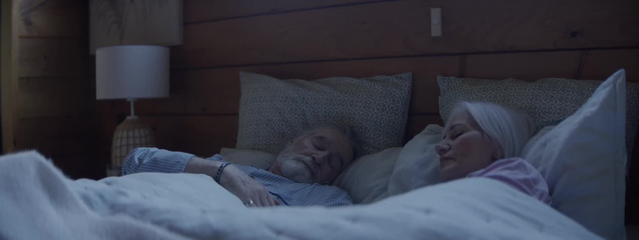 Man tosses and turns in bed beside a sleeping woman