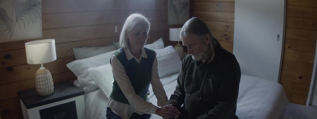 Couple sitting on the edge of the bed holds hands in a moment of mutual support
