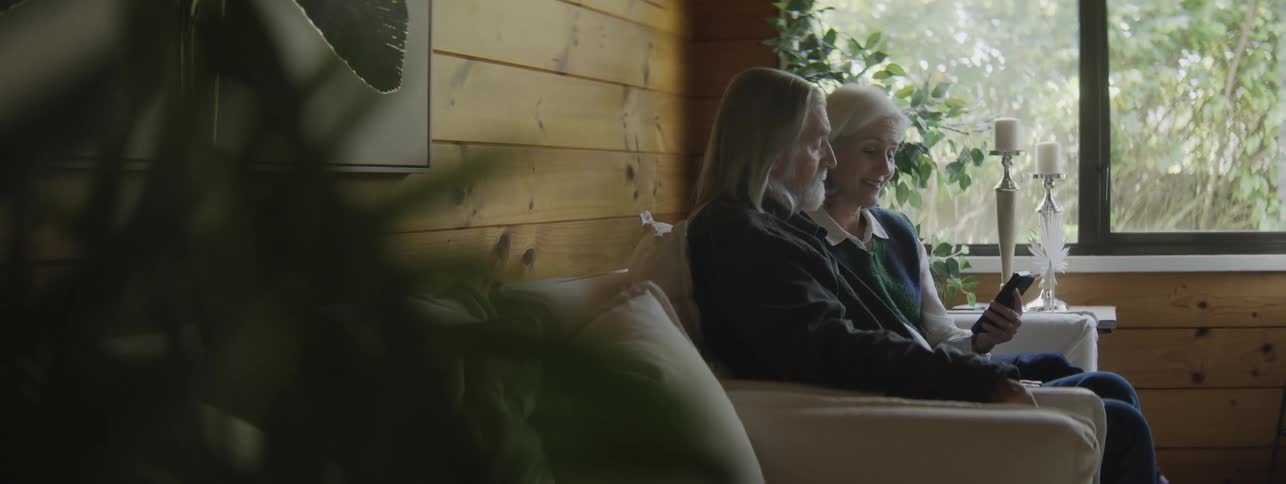 Elderly couple sitting on the couch looking at a phone together
