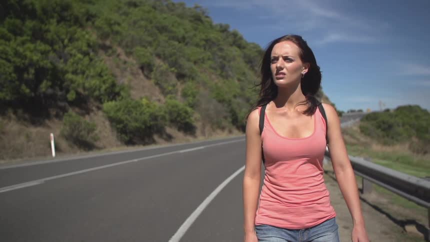A woman walking down a road looking around