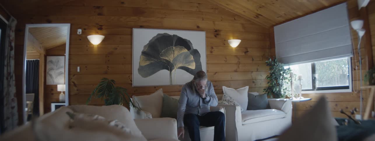 Elderly man coughing while cleaning a room with wooden walls