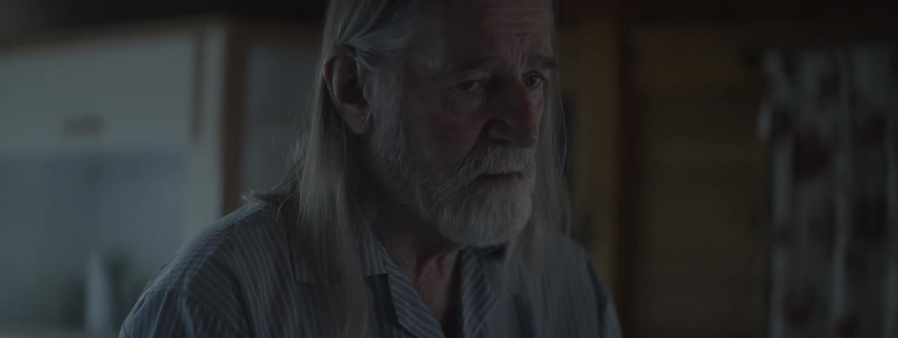 Elderly man with a serious thoughtful expression in a softly lit indoor setting