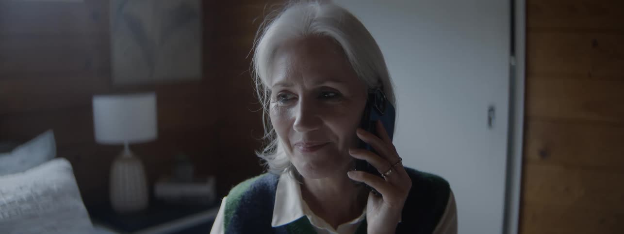Elderly woman smiling while talking on the phone in a cozy setting