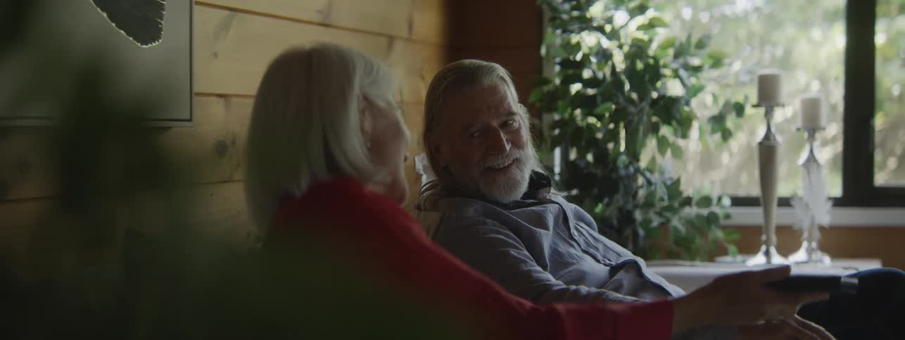 Couple smiles while relaxing together on the couch in a room lit by natural light