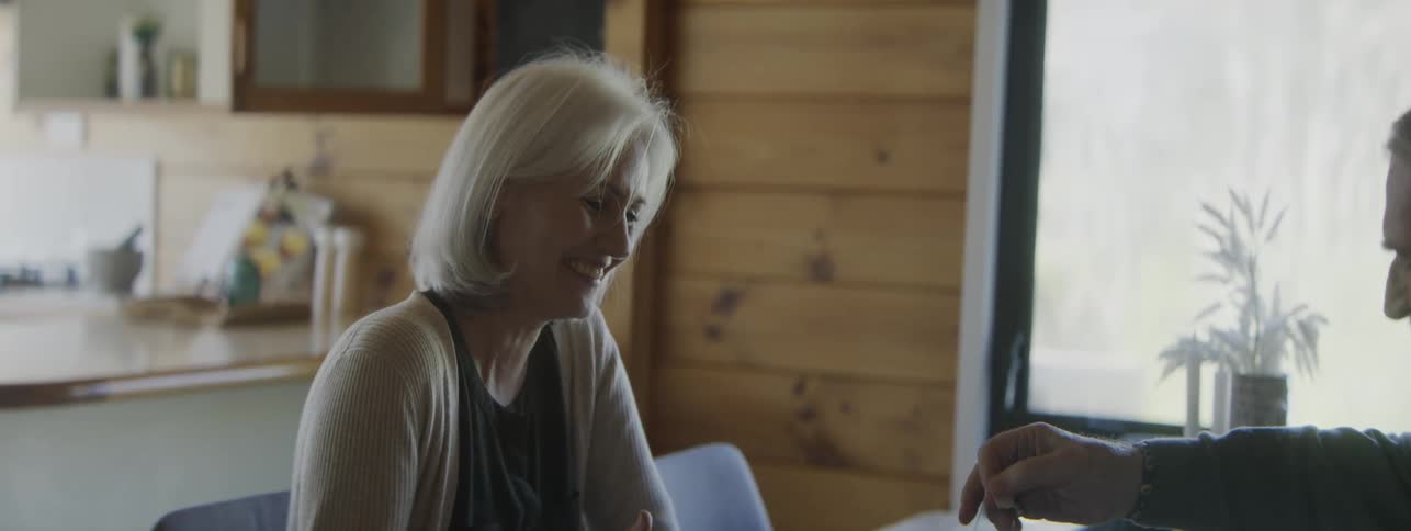 A mature couple sitting at a wood table taking breakfast in a kitchen setting
