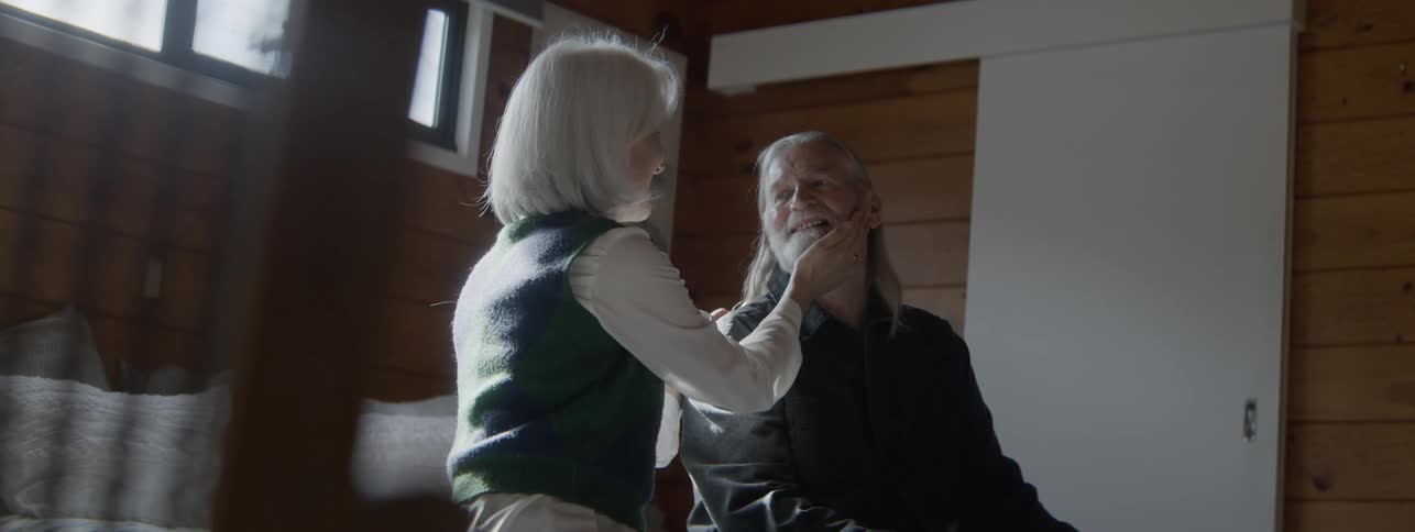 Woman caressing a seated mans face while smiling