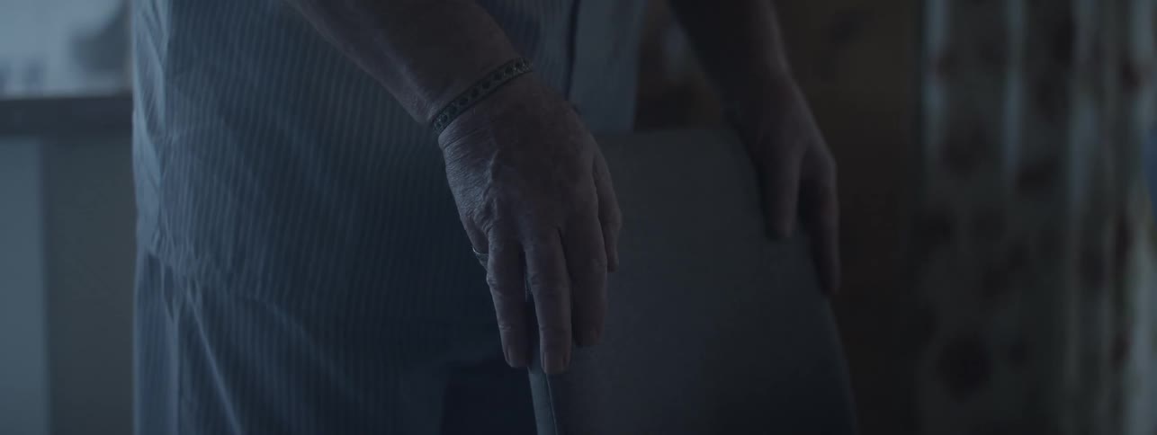 Aged hands holding the back of a chair in a domestic setting