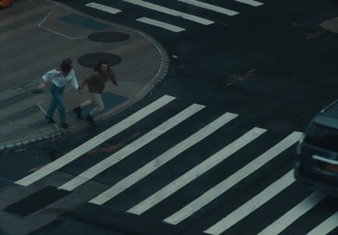 The man and woman hold hands while running across the street
