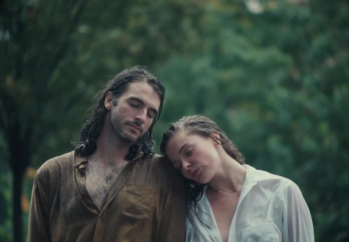 A man and a woman with wet hair standing outdoors in the rain in a moment of tenderness