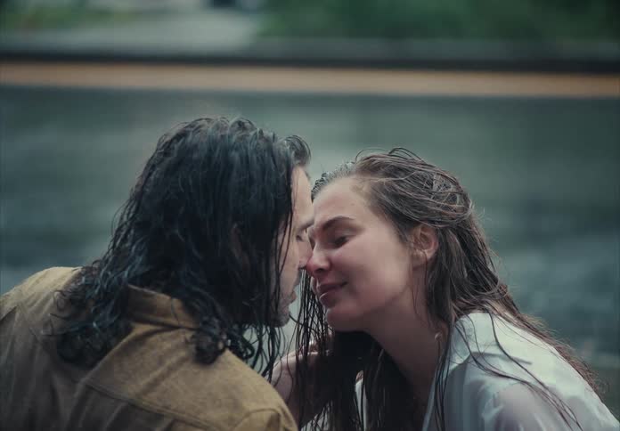 The couple kiss while it is raining