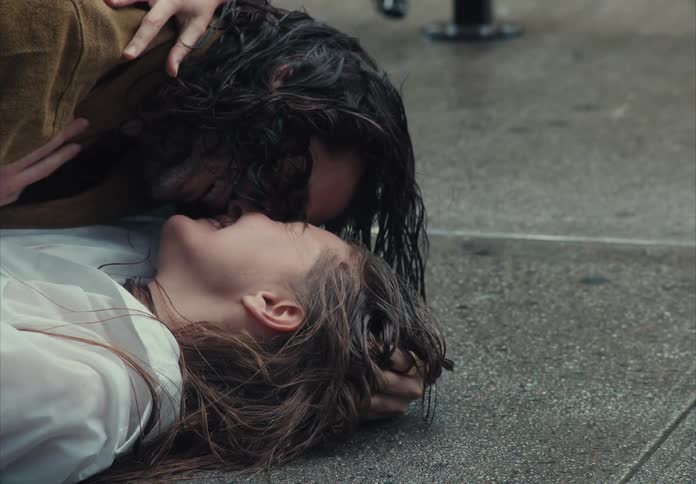 Couple kissing passionately while lying on the rainsoaked ground