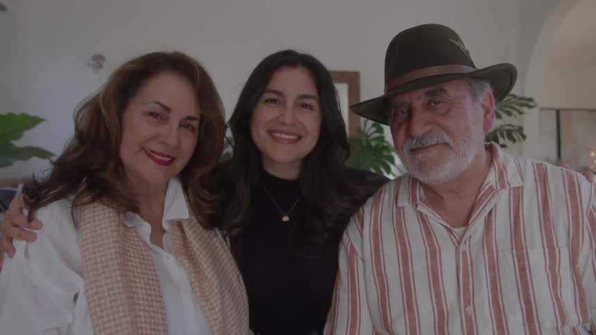 Three people smiling together in a welllit indoor setting