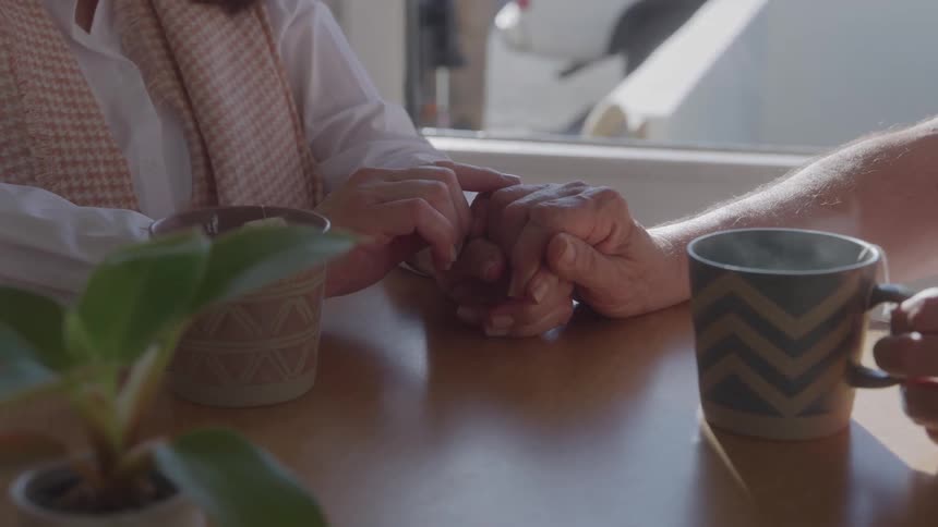 Two people sharing a gesture of affection while holding hands across the table