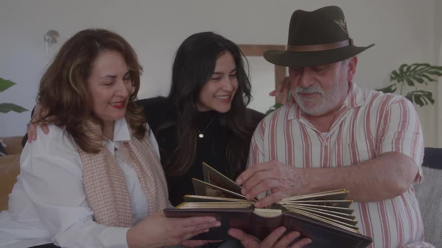 Family gathered smiles while flipping through an old photo album