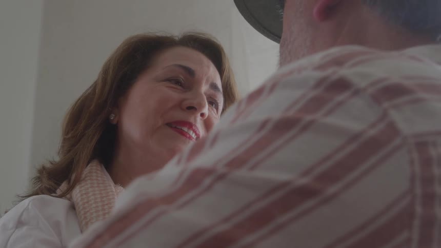 Older couple smiles into each others eyes while slow dancing indoors