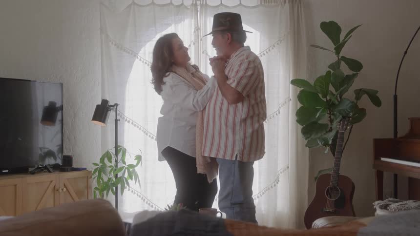 Couple dancing together in a room lit by natural light near the window