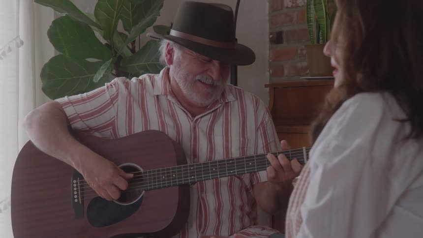 Man playing guitar and singing while talking with a woman