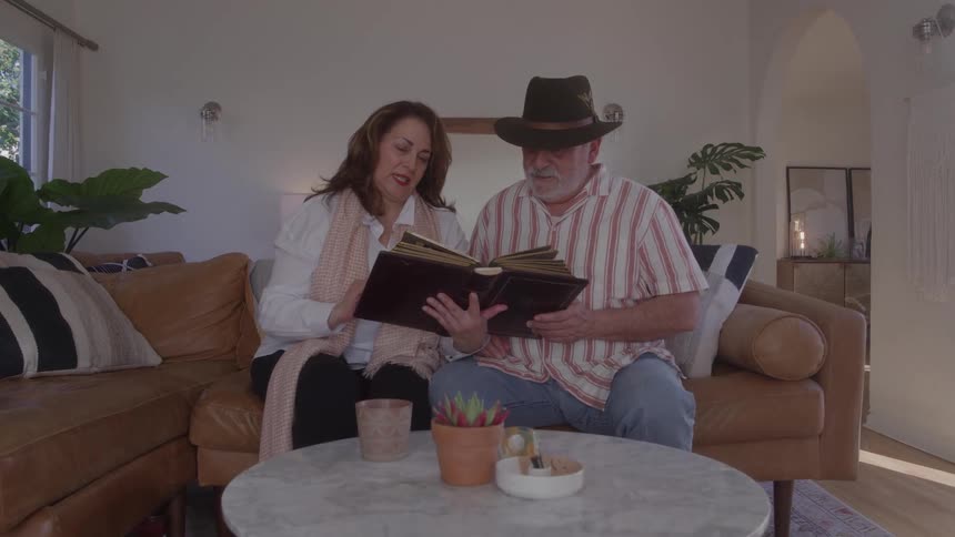 Couple sitting on the sofa looking at a photo album