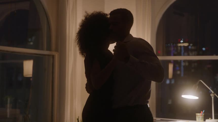 Couple dancing together indoors under night lighting