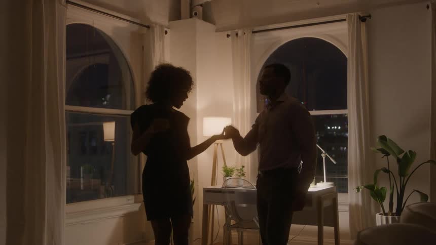 Couple dancing together in a softly lit room at night