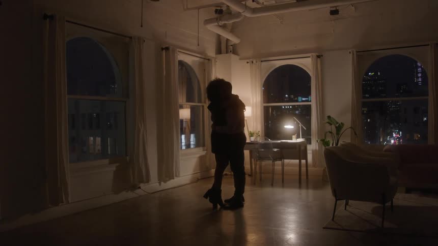 Couple embraces in the center of a softly lit room during the night