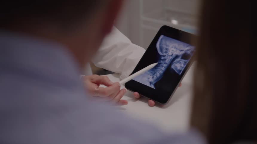 The doctor is pointing to an x ray on the tablet