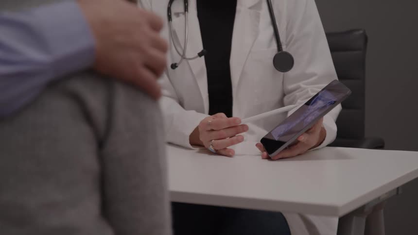 The patient points at the tablet the doctor is holding